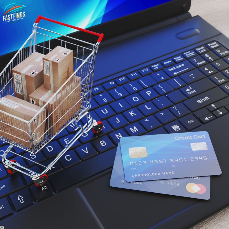 Shopping cart with boxes next to credit cards on a laptop keyboard.